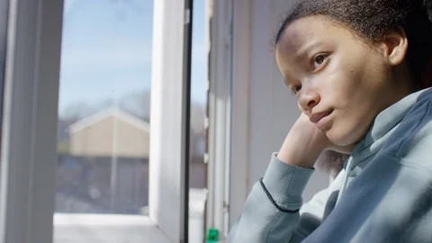 Young child looking out the window with a sad expression on her face Stock Footage 127863919