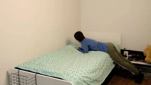 Young child makes the bed, pulling the blanket tight in a quiet bedroom, shot Stock Footage 330109561