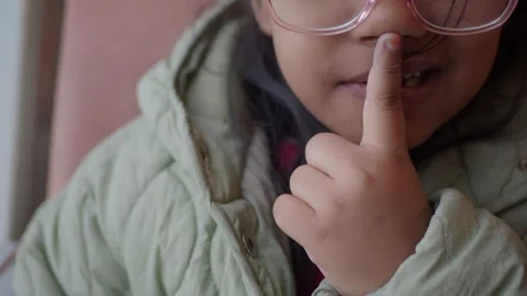 Young child making a hush gesture in cozy indoor setting Stock Footage 304852730