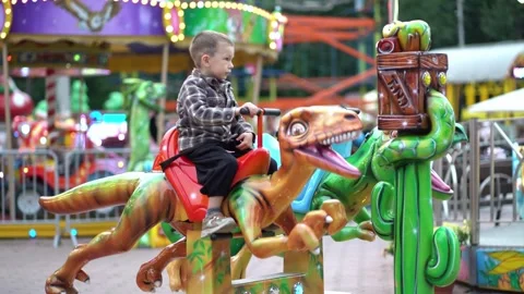 Young child on a mechanical raptor ride at a carnival fairground Stock Footage 344206476