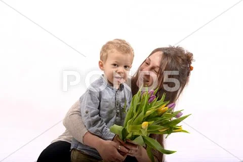 A young child offers flowers to his mom Stock Photos