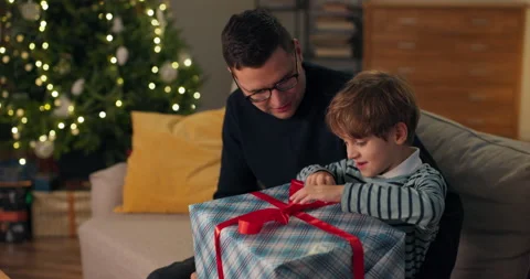 A young child opens a gift from Santa Claus, enjoys the gift tears the colored Видео 210440746