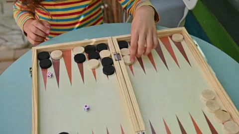 Young child playing backgammon on a wooden board at a table 스톡 동영상 290053578