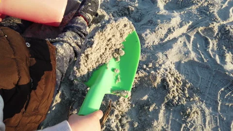 Young child playing in the beach sand with a green plastic trowel Stock-Footage 152881705