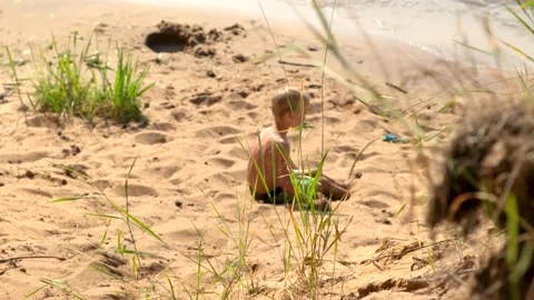 A young child playing on a beautiful sandy beach next to the waters edge Stock Footage 313599323