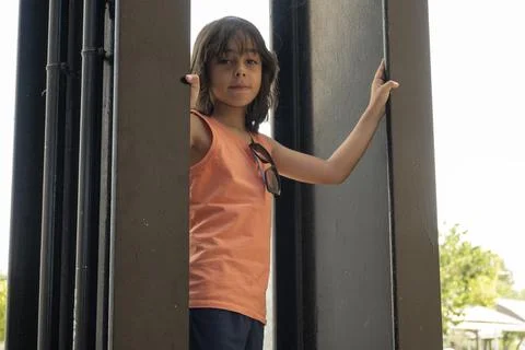 Young child playing hide and seek between black metal columns Stock Photos