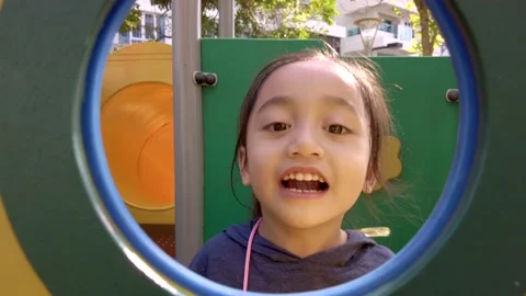 Young child playing peeks a boo through the window at the playground. Stock Footage 149982558