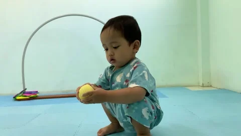 Young child playing with a yellow ball on a floor mat Видео 341914237