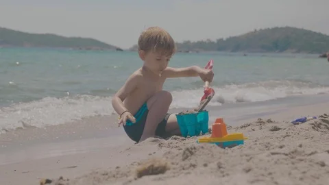 Young child plays on the beach making a sandcastle Stock Footage 88903739