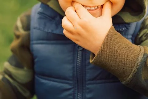 Young child plays in park while smiling, chewing finger on  sunny day . child Foto stock