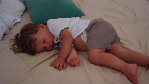 Young child resting curled on bed at home, seeking comfort during a quiet d.. Stock Footage 340430541