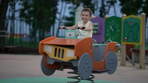 Young child rides colorful spring rider toy car in a park playground Vidéo 341410024