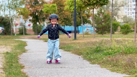 Young child rollerblading during an outdoor park walk Stock Footage 345634007