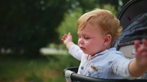 Young child sits in stroller, watching bubbles float past Stock-Footage 340885938