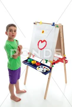 Young child standing at art easel Stock Photos