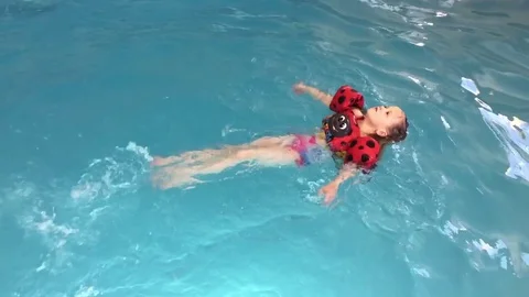 Young child swims on her back with floatation device HD Video stock 74097379
