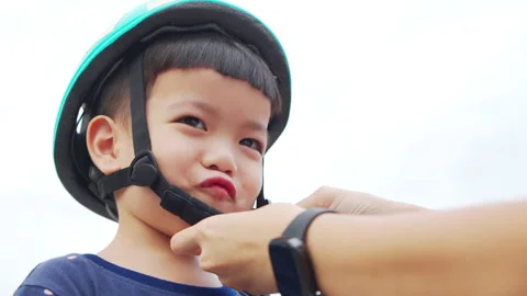 Young child wears a helmet while preparing for a fun outdoor activity on a sunny Stock Footage 300010989