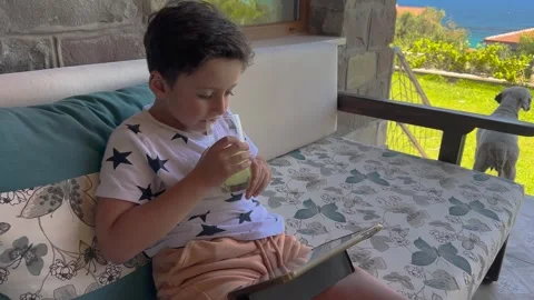 Young Children is drinking lemonade and watching, playing tablet, mobile ph.. Stock Footage 256249953