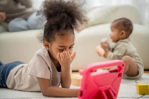 Young children engage with a tablet while playing and learning indoors in a.. Foto stock