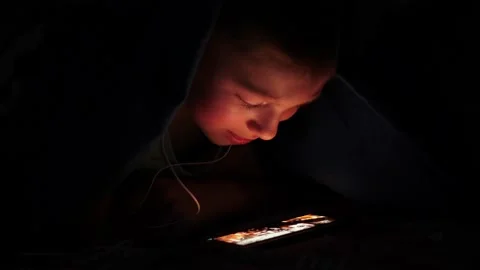 Young children using cell phone hidden under bed covers. Stock Footage 134896765