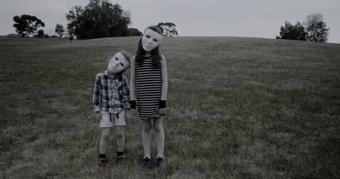 Young children wearing a white halloween masks stand creepily and scary Stock Footage