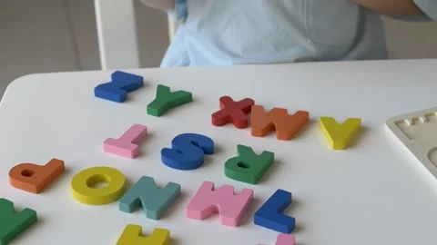 Young childs hand is actively sorting and placing vibrant alphabet letters on Stock-Footage 318293747