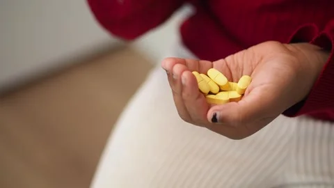 Young child's hands sorting yellow pills in palm, close-up detail, medical .. Stock Footage 331719418