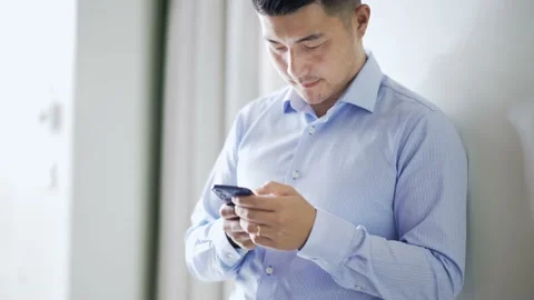 Young chinese businessman plays with mobile phone Stock Footage 195191353
