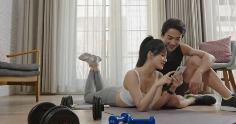 Young Chinese couple using smart phone after exercising,4K Stock Footage 228436654