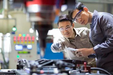 Young Chinese engineers checking machine in the factory Foto stock