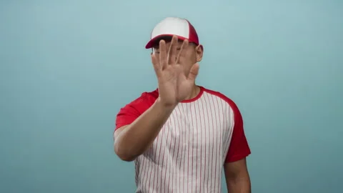 Young chinese man in a baseball uniform gestures stop against an isolated b.. Stock Footage 311500033
