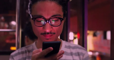 Young chinese man using mobile phone at night on Hong kong tram. Slow motion, sh Stock Footage 201094115