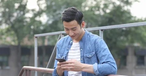 Young Chinese man using smartphone outdoors,4k Stock Footage 118040427