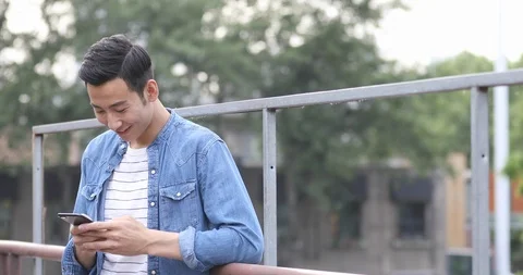 Young Chinese man using smartphone outdoors,4k Stock Footage 118040540