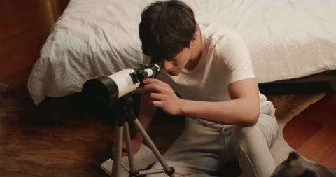 Young Chinese man using telescope at home,4K Stock Footage 156395412