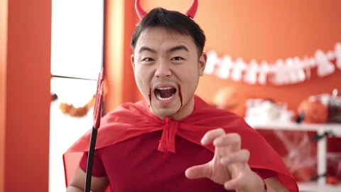 Young chinese man wearing devil costume doing scare gesture at home Stock Footage 233426073