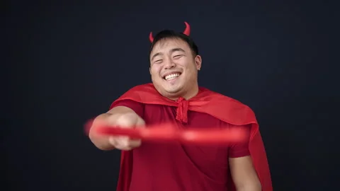 Young chinese man wearing devil costume holding trident over isolated black.. 動画素材 234655215