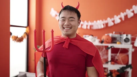 Young chinese man wearing devil costume holding trident at home 動画素材 237846791