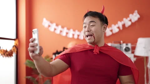 Young chinese man wearing devil costume having video call at home Stock Footage 237846815