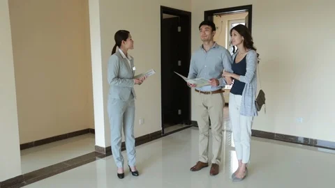 Young Chinese realtor showing new house to young couple,HD Stock Footage
