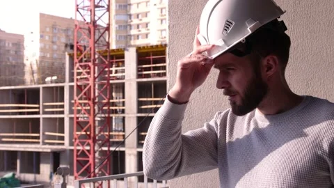 Young civil engineer with a beard in a white hard hat at a construction site Stock-Footage 154052676
