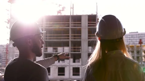 Young civil engineer with a beard in a white helmet and a beautiful female Stock Footage 154052803