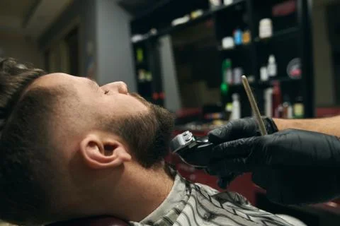 Young client having his dark beard shaved by male master Stock Photos