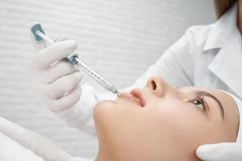 Young client receiving procedure botox of lips. Stock Photos