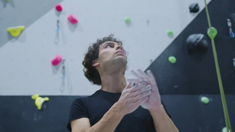 Young climber preparing with chalk, looking up towards the climbing wall with Stock Footage 277278361