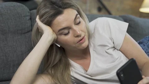 Young clothing lying down on sofa and having video call Video stock 233435236