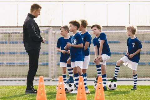 Young coach explaining training rules to children school soccer team Stock Photos