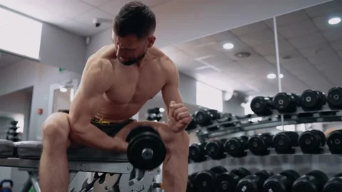 The young coach shows how to correctly lift the dumbbell with one hand, in the Stock Footage 156508157