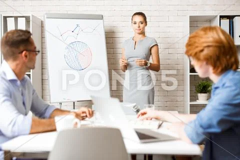 Young coach standing by whiteboard during presentation Stock Photos