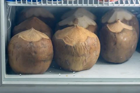 Young coconuts with tops cut open, neatly stored inside a refrigerator for .. Stock Photos